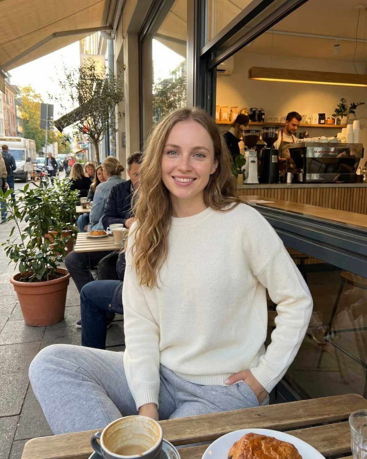 Model wearing a Biot Pullover at a café, showcasing its luxurious wool feel and relaxed fit for casual outings.