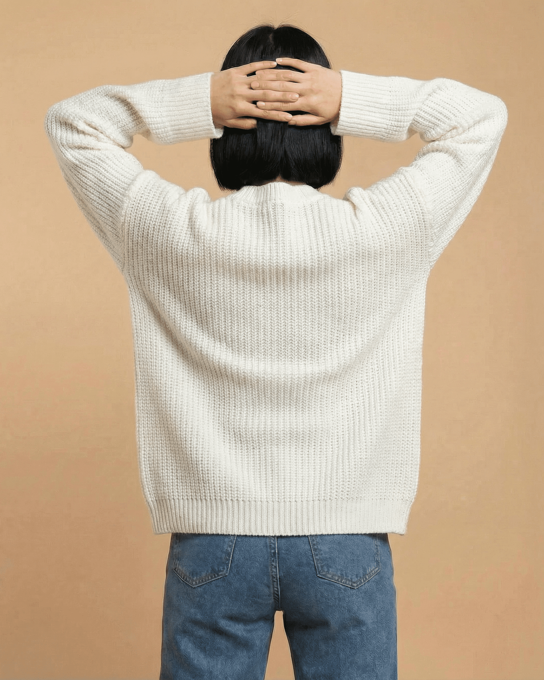 Back view of woman wearing the Elara Cardigan by RAMBLION, showcasing its cozy knit texture and relaxed fit.