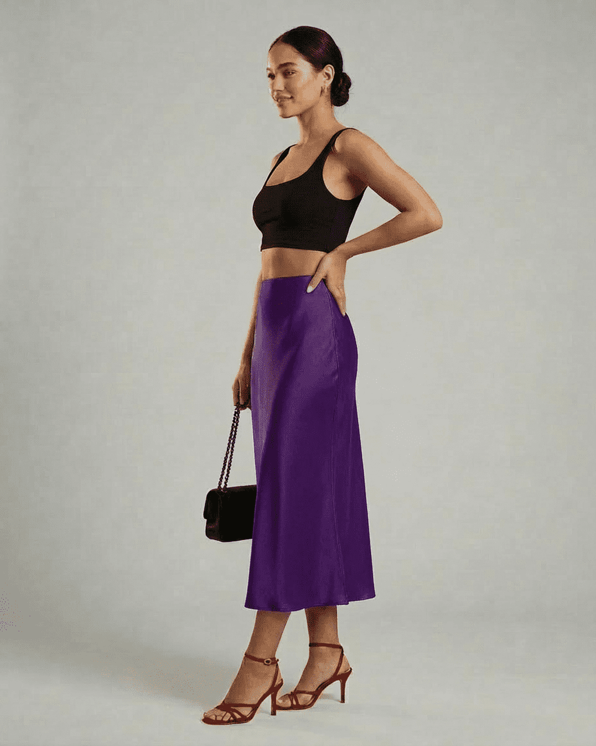 Model showcasing RAMBLION Amethyst Midi Skirt in vibrant purple, paired with a black crop top and red heels.