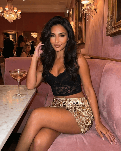 Aurelia Mini Skirt styled with a black top, showcasing gold sequin details in a chic setting by RAMBLION.