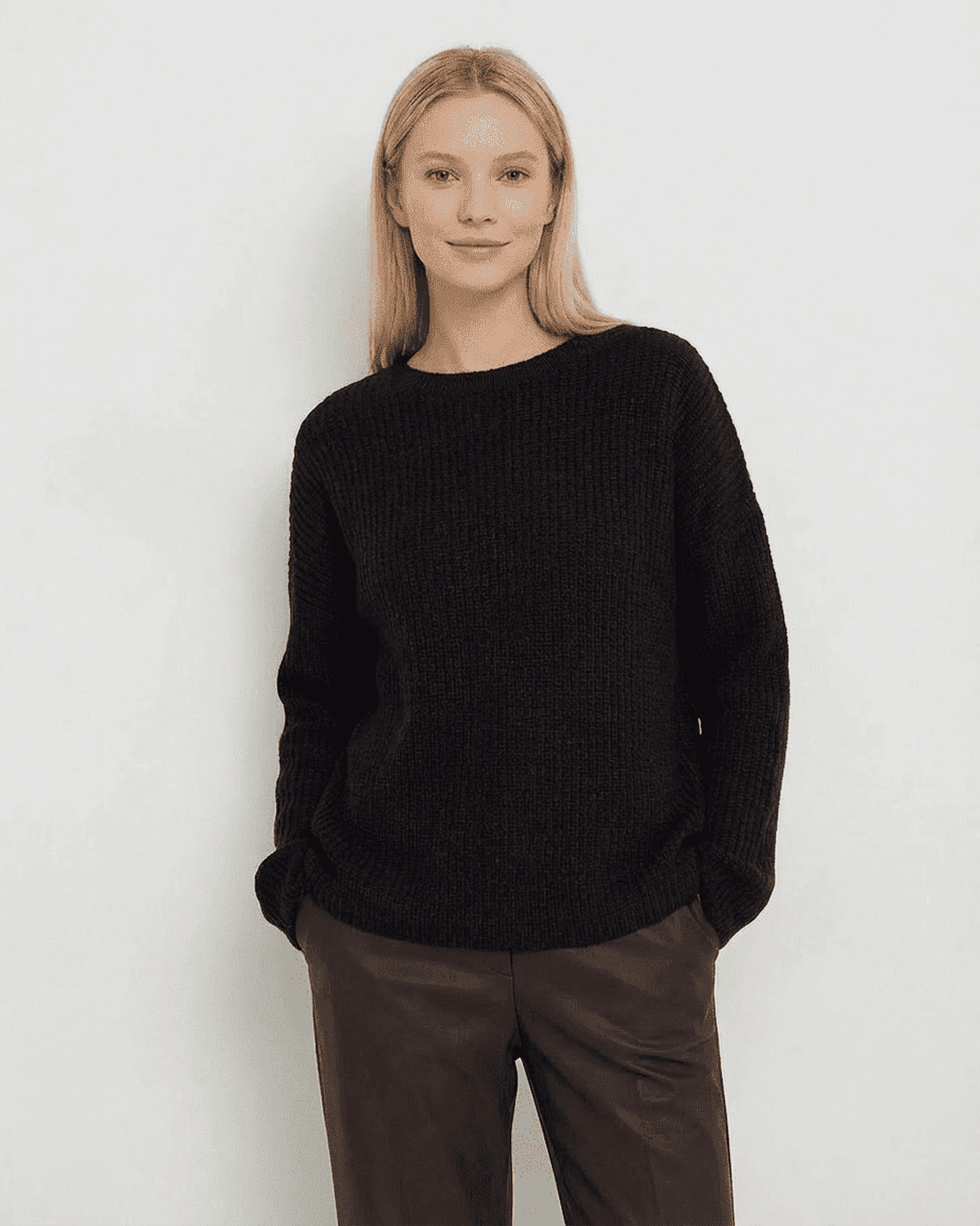 Woman wearing the Beja Sweater by RAMBLION in black, featuring a cozy ribbed knit and relaxed fit, perfect for cooler occasions.
