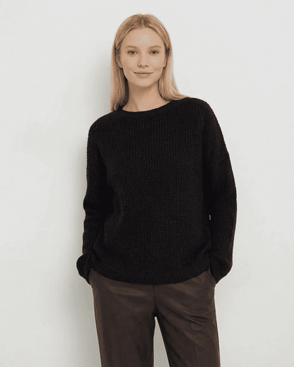 Woman wearing the Beja Sweater by RAMBLION in black, featuring a cozy ribbed knit and relaxed fit, perfect for cooler occasions.