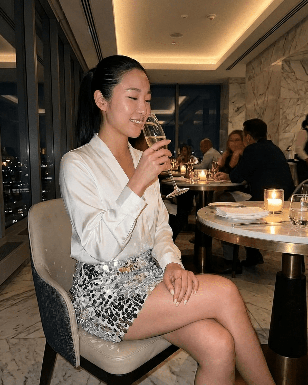 Celeste Mini Skirt worn by a woman enjoying a drink in an elegant restaurant setting, showcasing RAMBLION brand glamour.