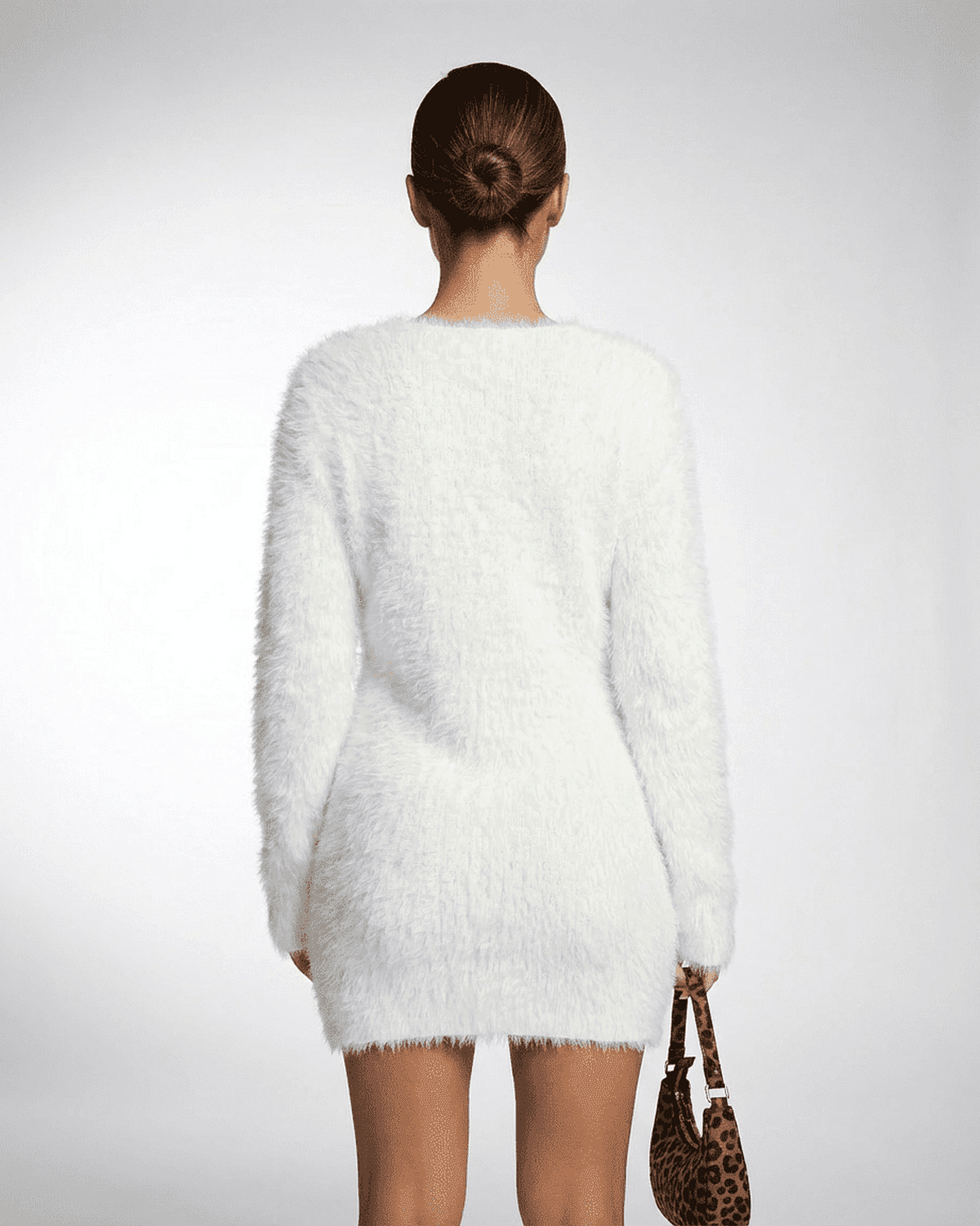 Back view of a model wearing the Elara Sweater in white, showcasing its plush texture and stylish design.