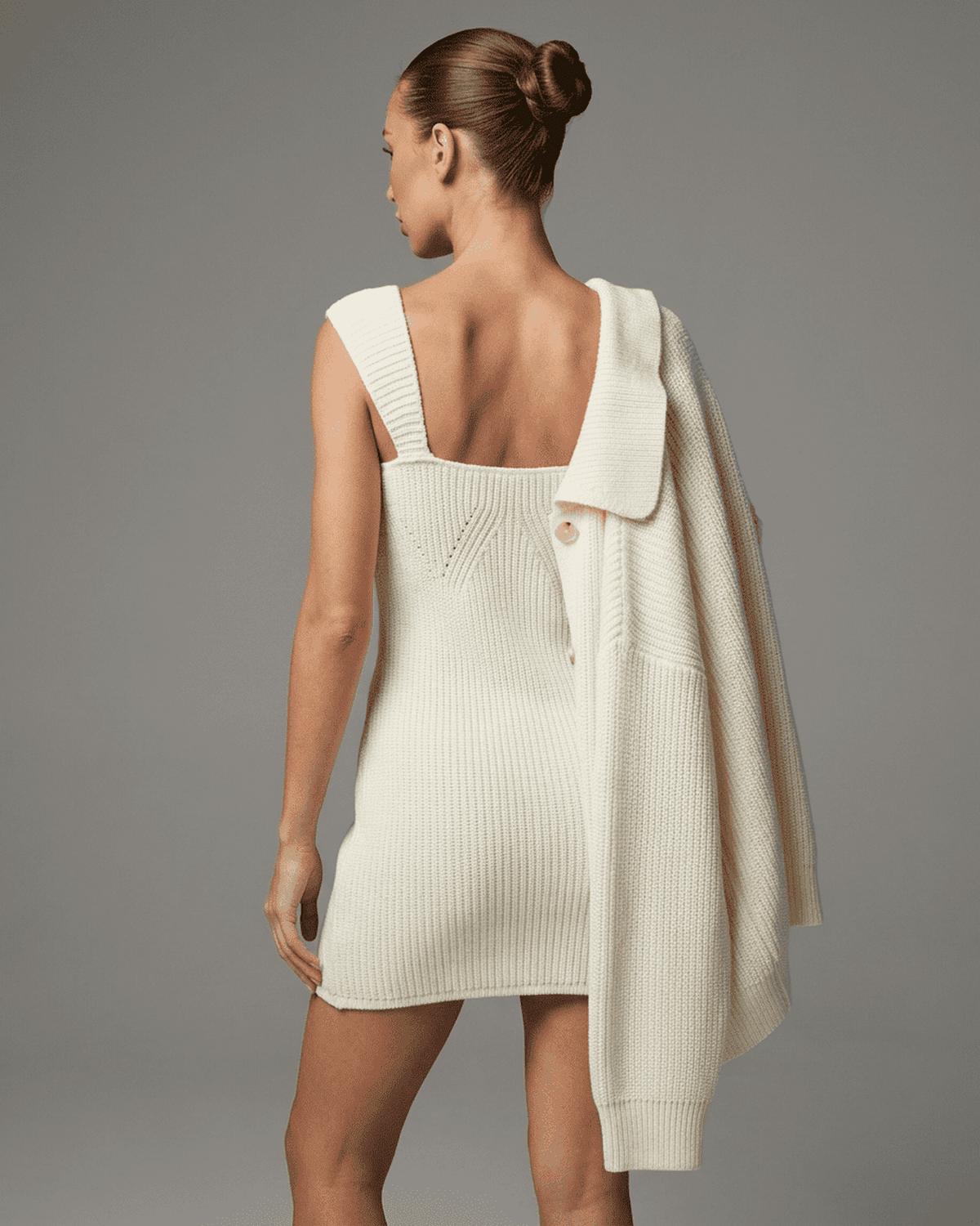 Elysia Mini Dress in soft white knit with sleeveless design and structured texture, modeled by a woman from the back.