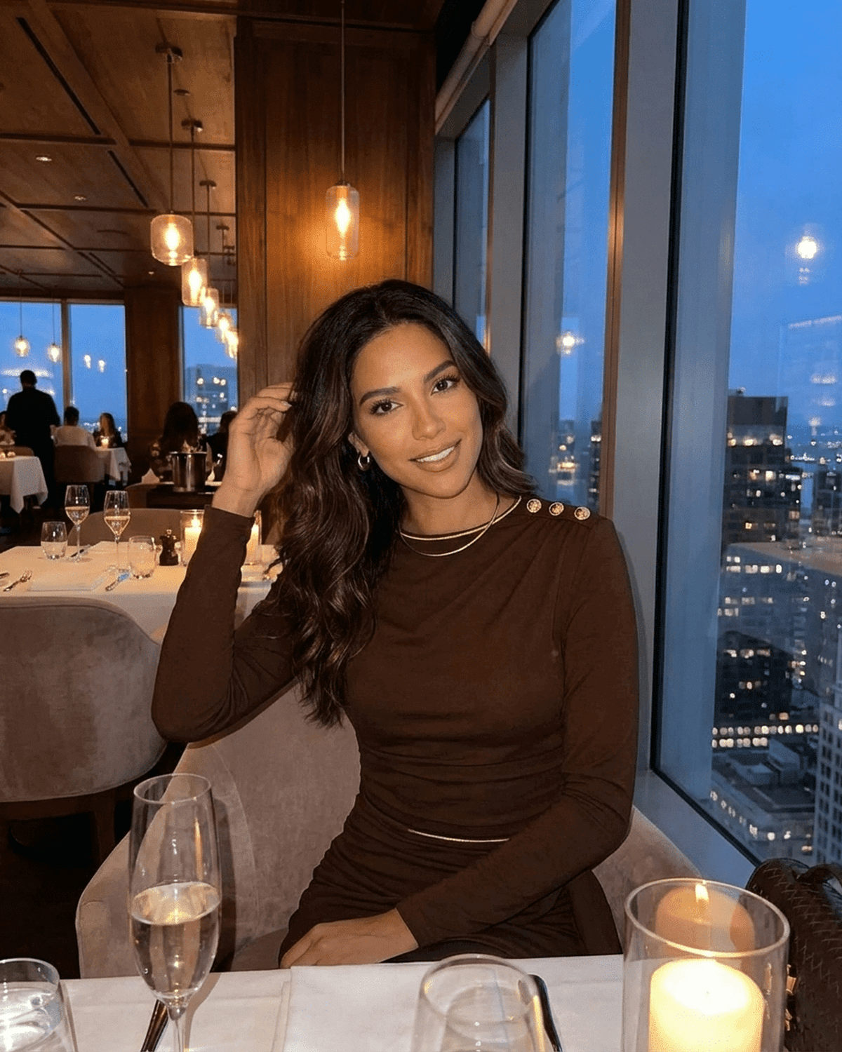 Elegant woman wearing Fife Mini Dress, enjoying dinner in a high-rise restaurant with city views.