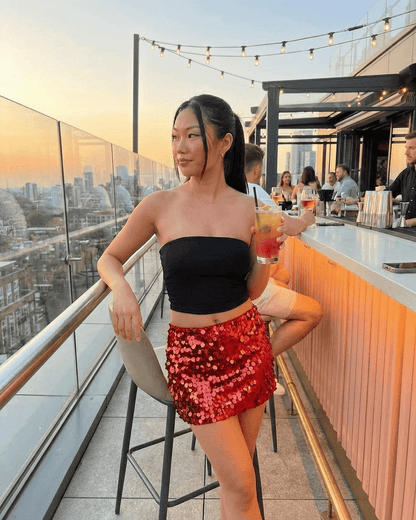Flamenco Mini Skirt: A woman in a red sequin bodycon mini skirt and black top at a rooftop bar.