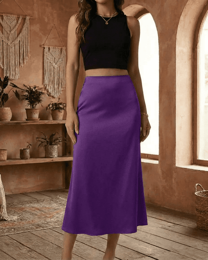 Model showcasing the Amethyst Midi Skirt by RAMBLION in vibrant purple satin, elegantly styled with a black crop top.