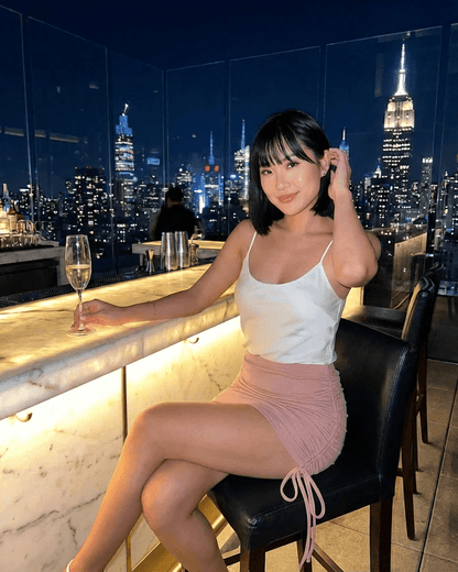 Blush Mini Skirt by RAMBLION, high-waisted bodycon style showcased in an elegant setting with city skyline background.