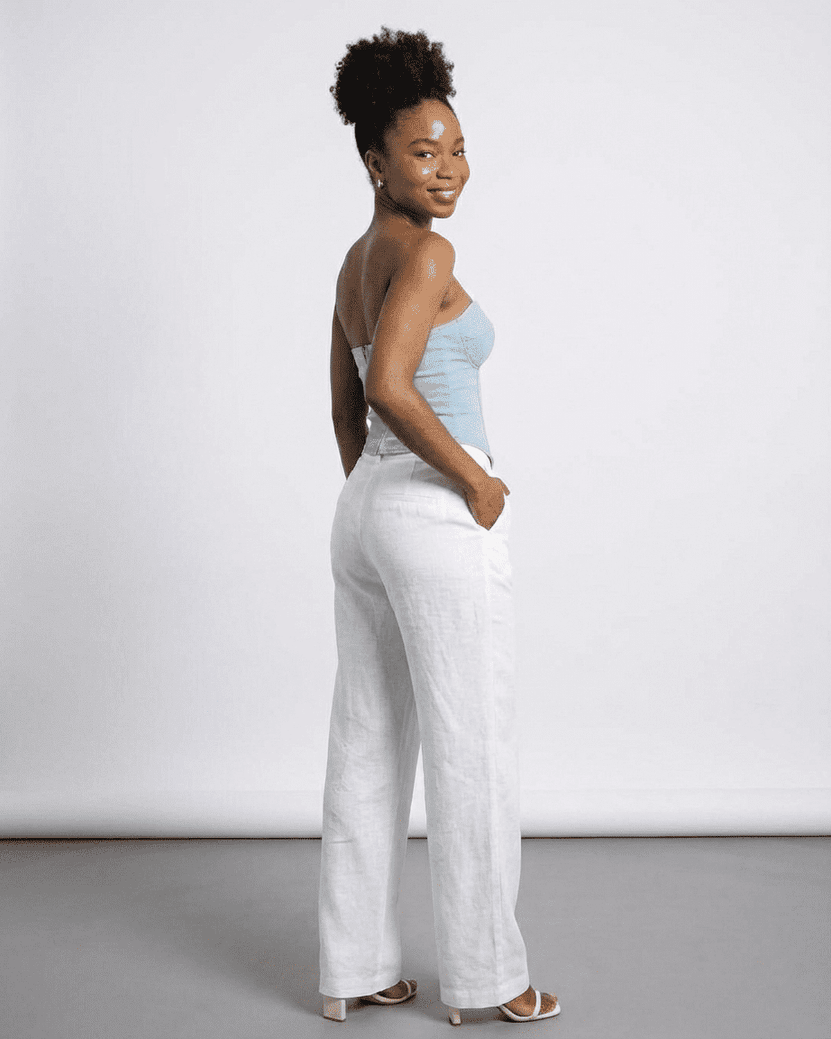 Denali Corset Top by RAMBLION, showcasing a woman in a faux denim bustier with stylish white linen pants.