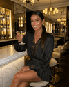 Woman in a Noir Mini Dress with lace detail holding a cocktail at a stylish bar.