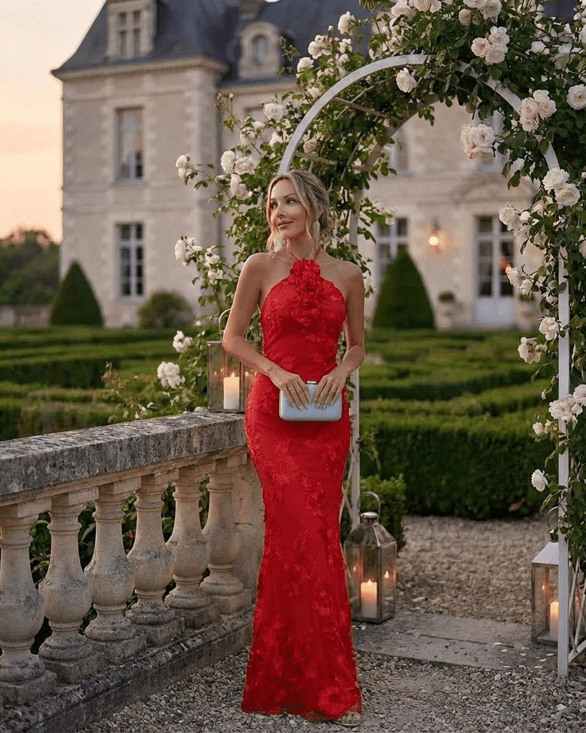 Rosalia Maxi Dress by RAMBLION, elegant halter neck design in bold red with 3D floral detail in a picturesque garden setting.