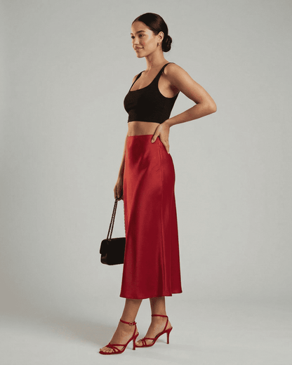 Model showcasing Rosalia Midi Skirt by RAMBLION, a refined satin mermaid midi skirt in rich red hue.