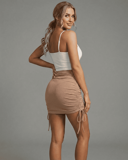 Model wearing RAMBLION Sand Mini Skirt featuring adjustable drawstrings and a flattering bodycon fit.