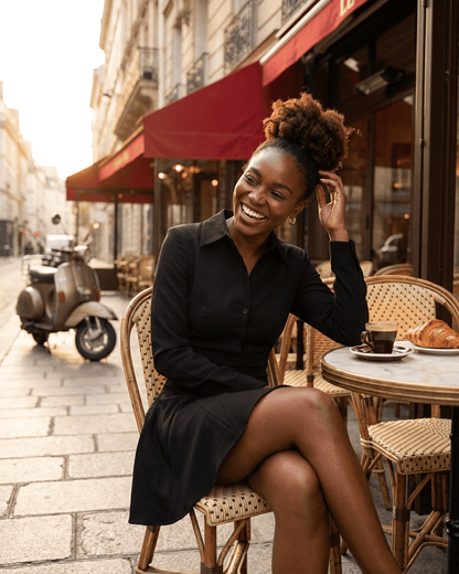 Woman enjoying coffee in a cafe while wearing the Vesta Mini Dress by RAMBLION, showcasing elegance and style.