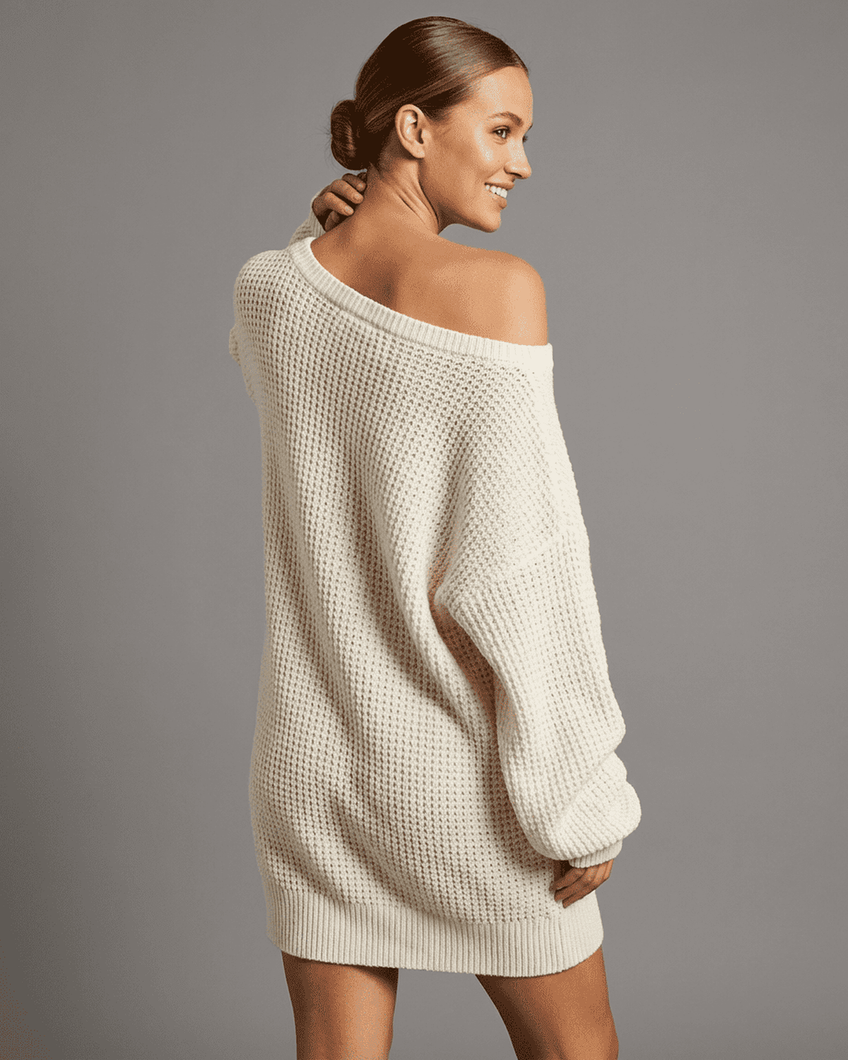 Model wearing the Aurora Mini Dress by RAMBLION, showcasing the off-the-shoulder design and cozy knit fabric.