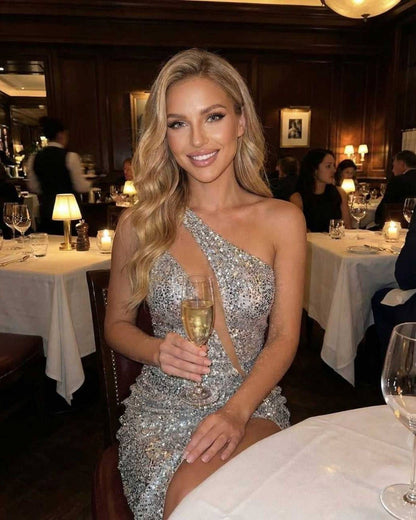Liri Mini Dress elegantly worn at dinner, featuring sequins, an asymmetric neckline, perfect for evening occasions by RAMBLION.