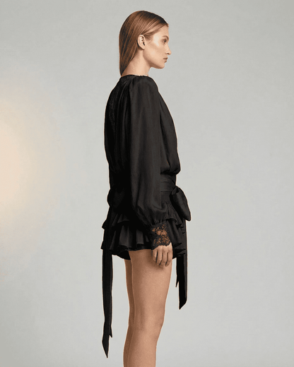 Side view of a model wearing the RAMBLION Noir Mini Dress with lace detail and long sleeves.