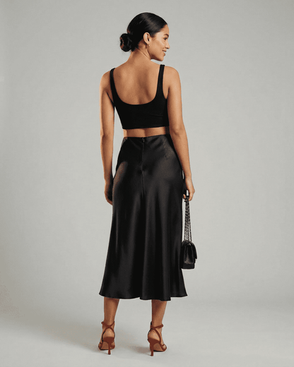 Model showcasing the Noirelle Midi Skirt by RAMBLION, featuring a sleek satin mermaid design in classic black.