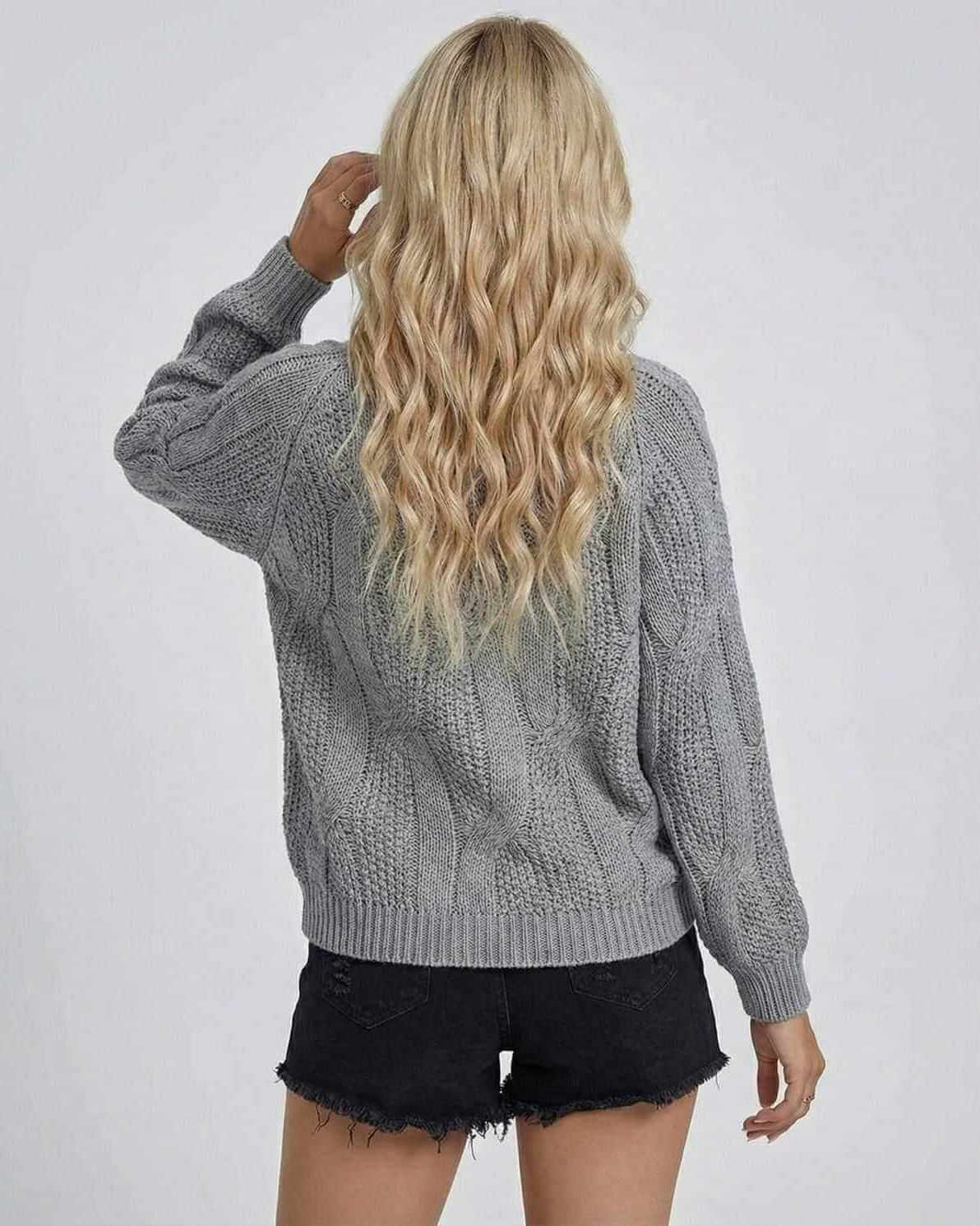 Back view of a woman wearing the RAMBLION Orion Sweater, showcasing its cable-knit design and relaxed fit.