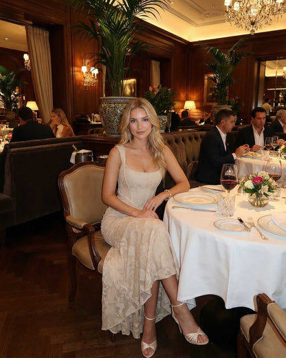 Ovra Maxi Dress at a dimly lit restaurant, showcasing elegance with a square neckline and romantic beige hue.