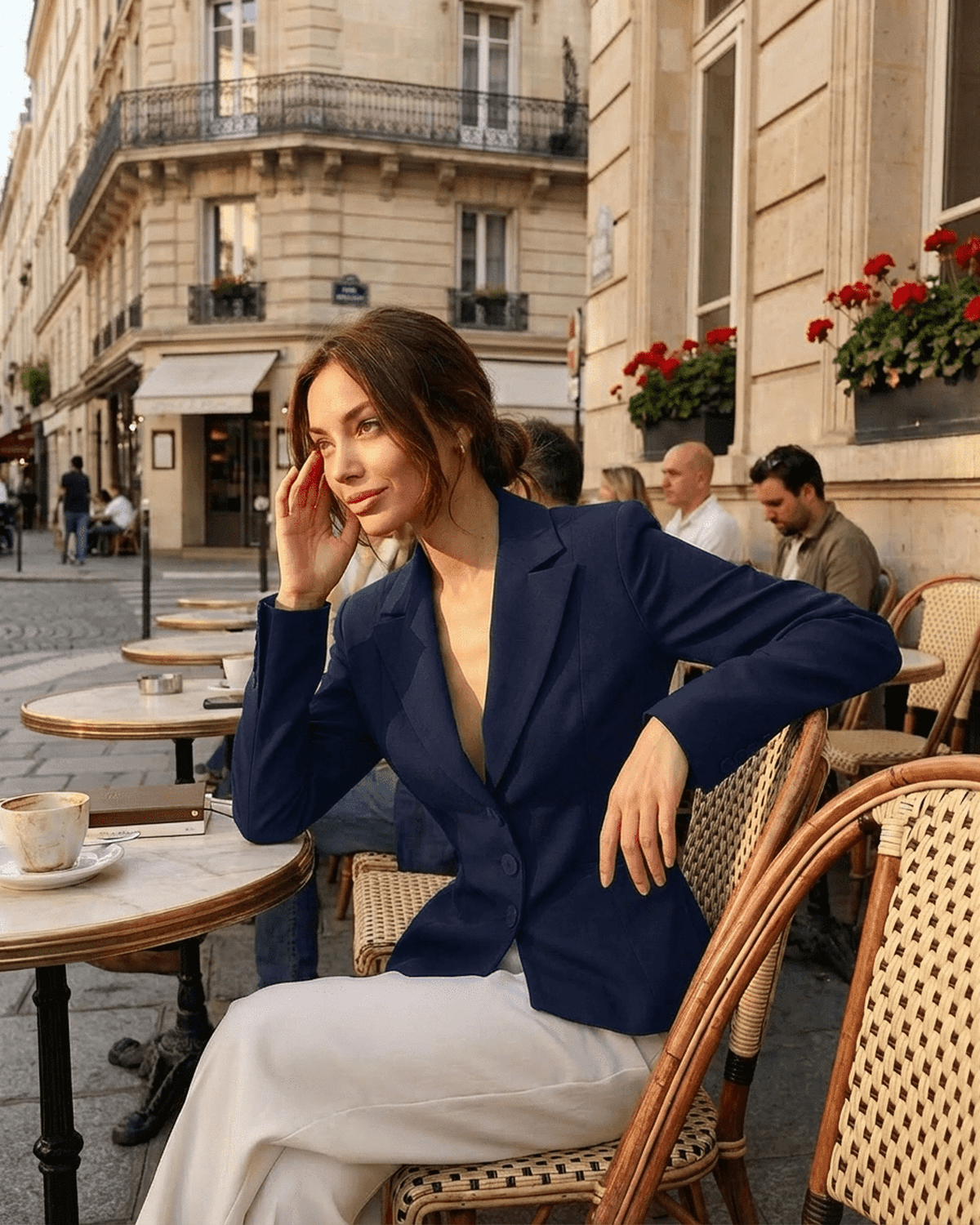 Woman wearing an Aurora Blazer, a fitted navy tailored blazer, at a Parisian café.