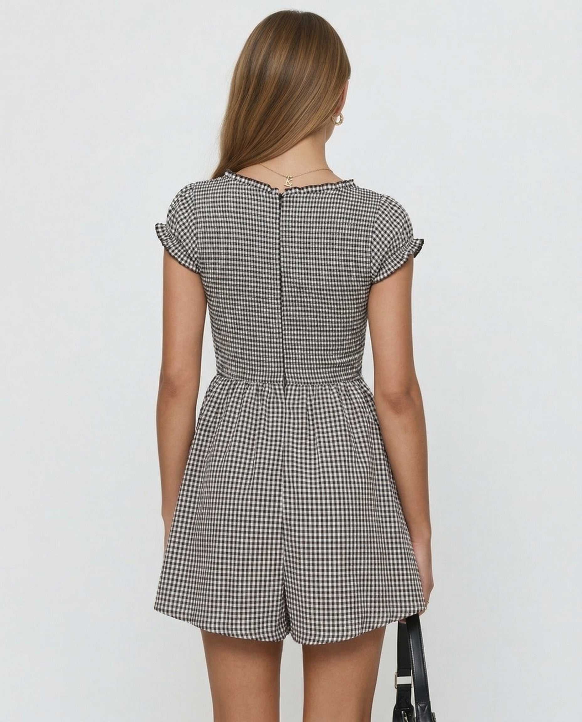 Back view of a stylish black and white checkered romper by RAMBLION, showcasing a playful and elegant design.