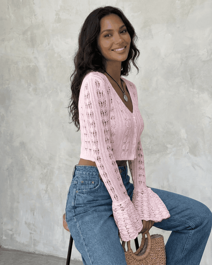 Woman wearing a pink Blossom Cardigan with flare sleeves, paired with high-waisted jeans.