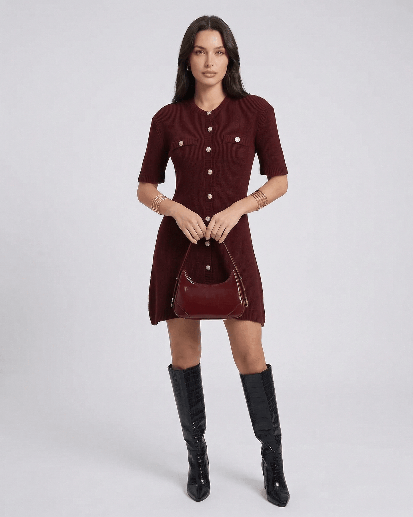 Pantelleria Mini Dress in burgundy with button details, styled with knee-high black boots and a chic handbag.