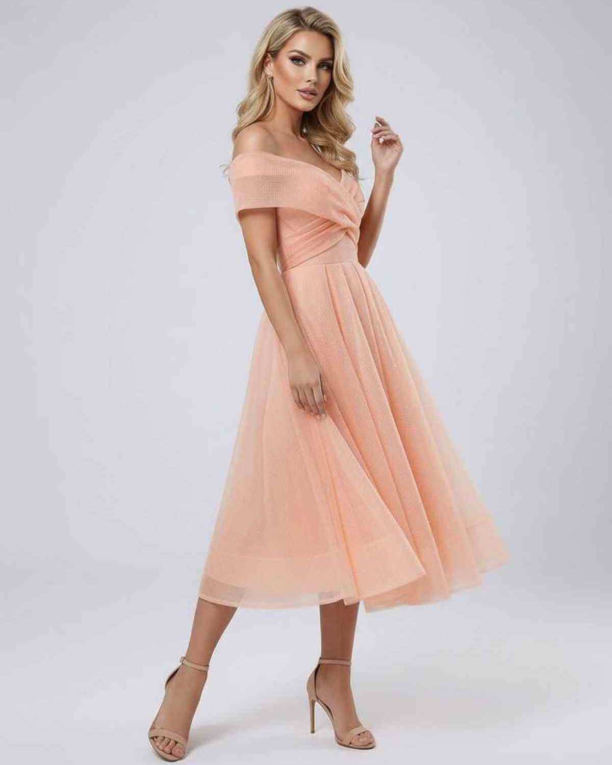 Celeste Midi Dress worn by a model, showcasing its off shoulder design and flowing midi length in a soft peach color.