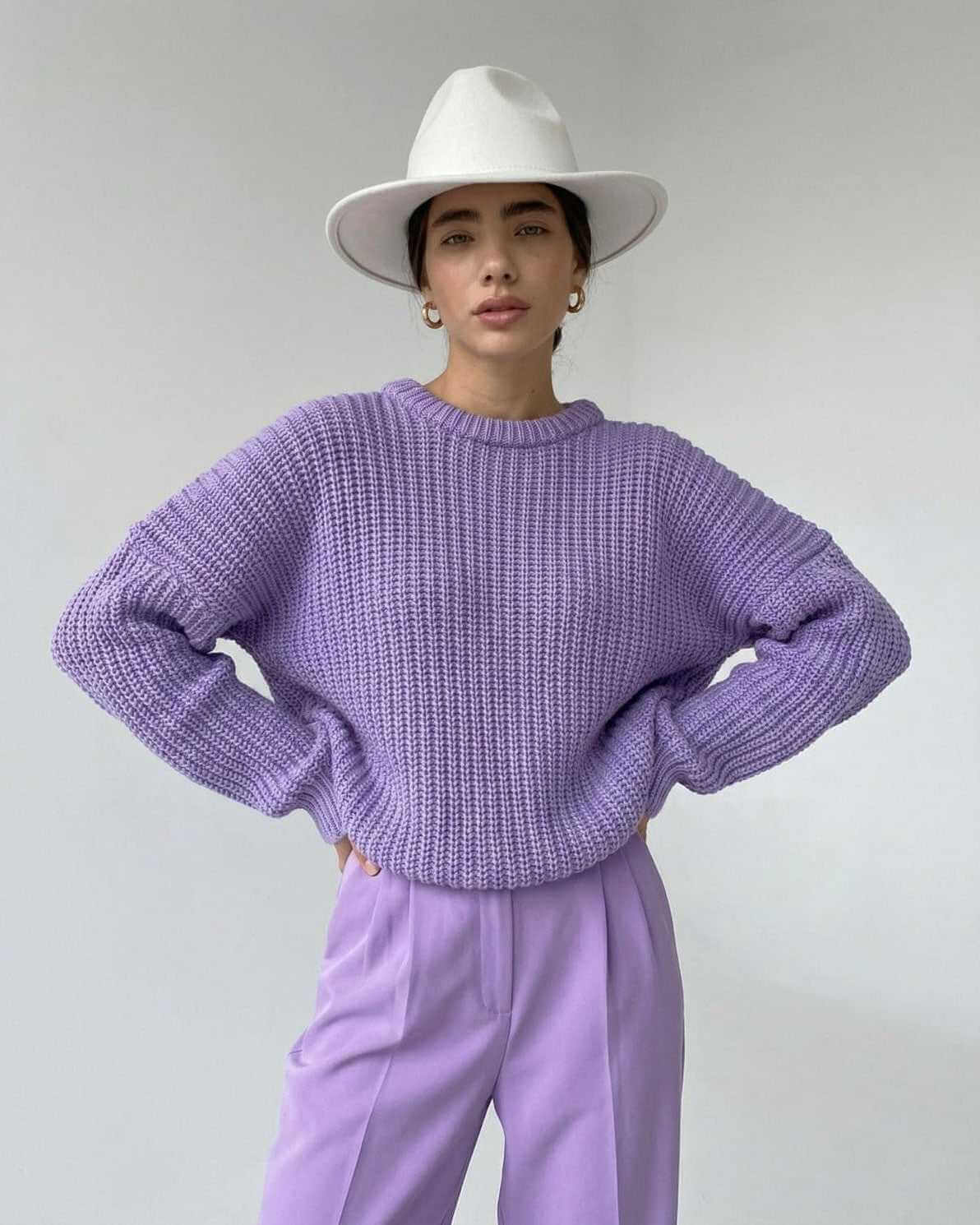Lavande Sweater by RAMBLION in textured knit with a relaxed fit, styled with a white hat and pastel trousers.