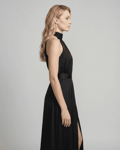 Profile view of Noctis Maxi Dress, a sleek black sleeveless turtleneck dress by RAMBLION with high waist and side slit.