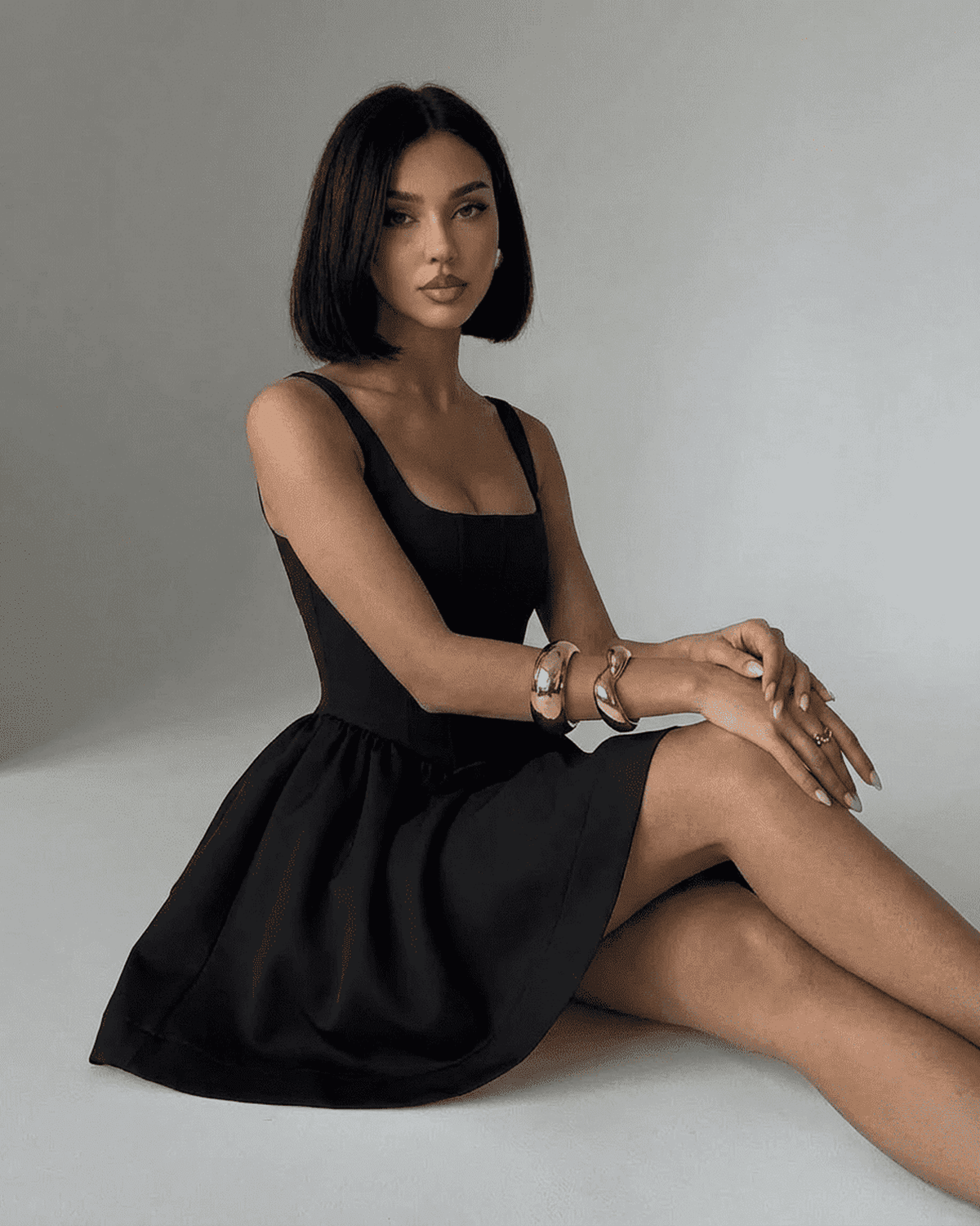 Woman wearing the Nocturne Mini Dress, a black structured corset mini with square neckline and sculptural design.