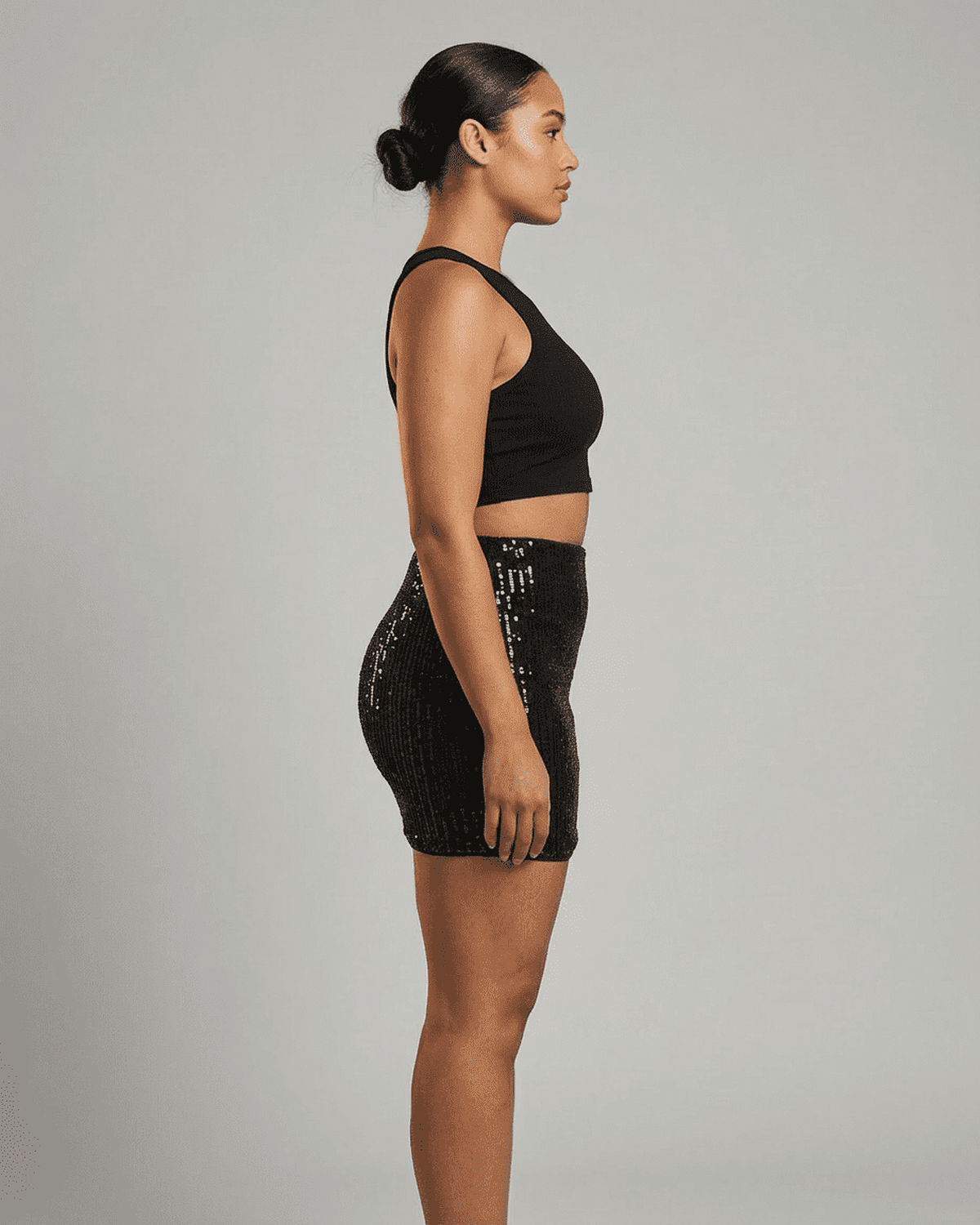 Noiré Mini Skirt showcased on model from the side, featuring a sleek high waist and shimmering sequin finish.