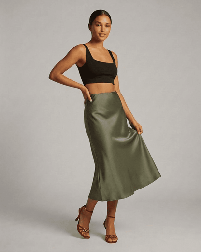 Olivia Midi Skirt - Satin mermaid midi skirt in olive green, paired with a black top, showcasing elegant silhouette