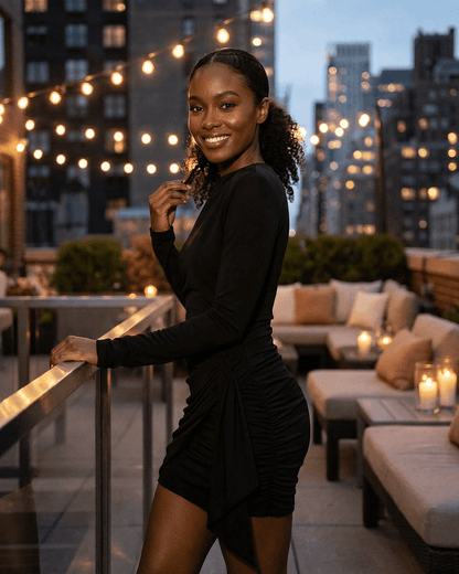 Model wearing Onyx Mini Dress with ruched detailing, smiling on a rooftop terrace with city lights.