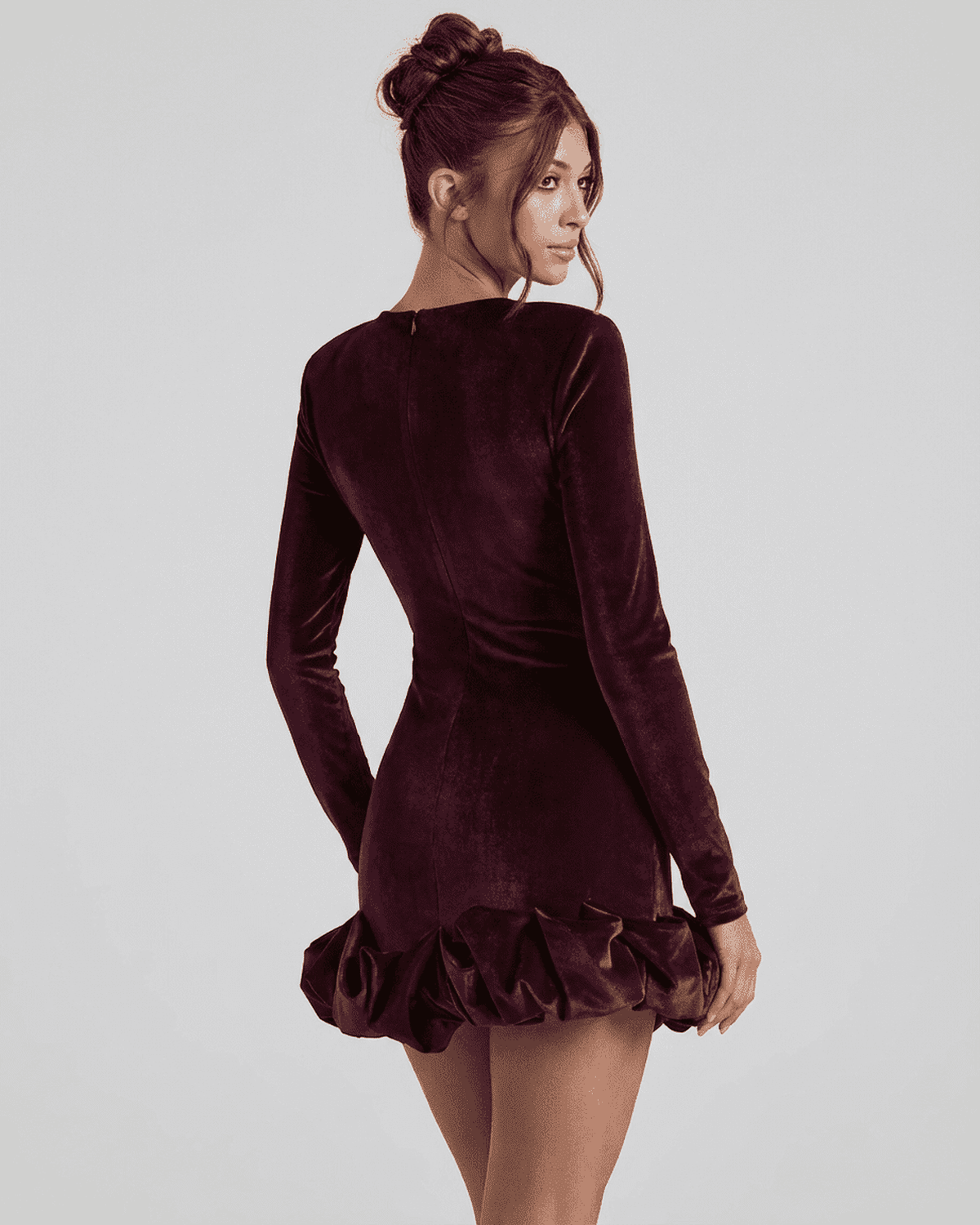 Rear view of the Velora Mini Dress, showcasing the dramatic pleated hem in deep burgundy fabric.