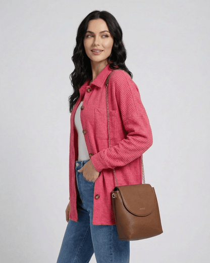 Woman wearing a RAMBLION Verona Jacket in pink waffle knit, styled casually with denim jeans and a brown handbag.