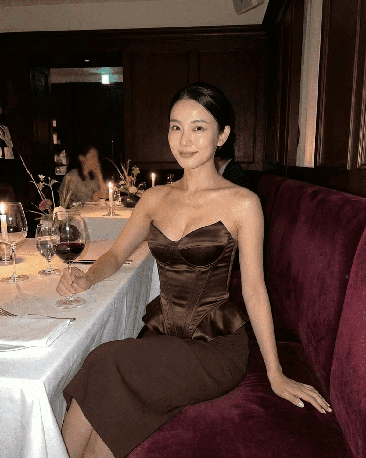 Sienna Corset Top worn by a woman in a restaurant, featuring strapless satin structure and rich brown tone.