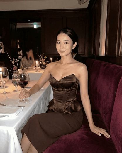 Sienna Corset Top worn by a woman in a restaurant, featuring strapless satin structure and rich brown tone.