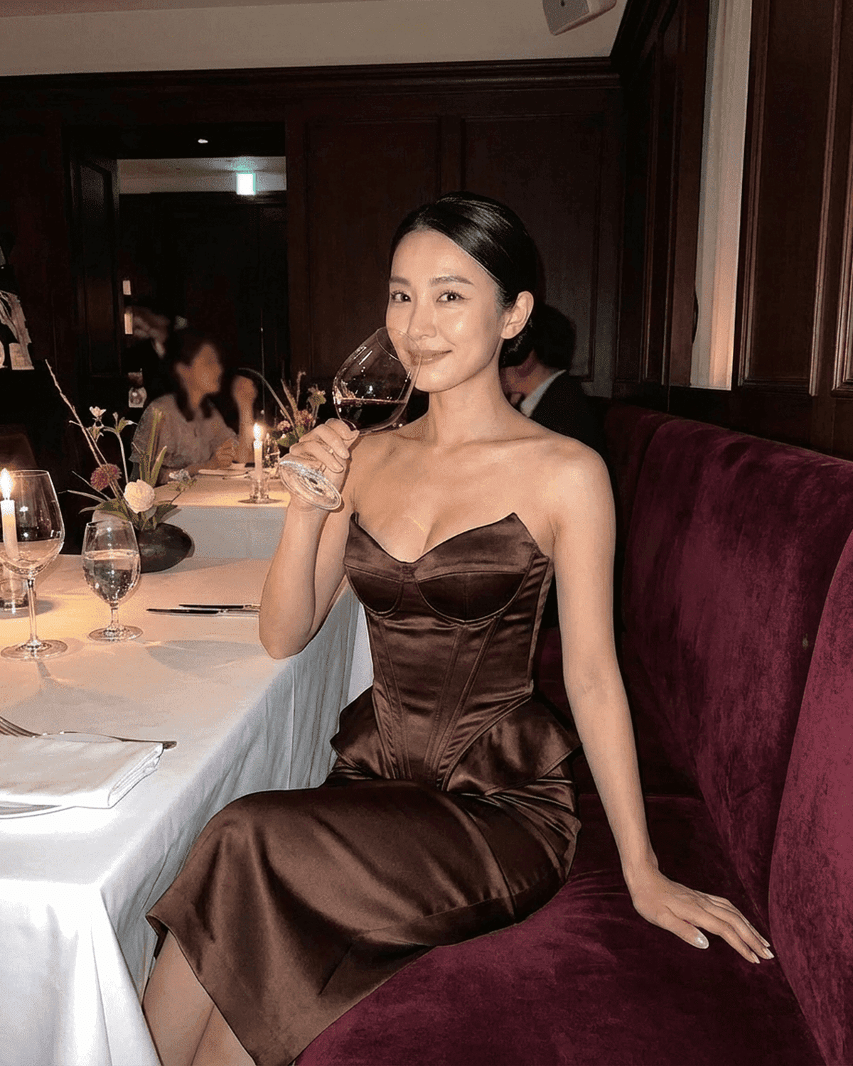 Sienna Corset Top worn by a woman in a strapless satin structure, featuring asymmetrical finish in a sophisticated setting.