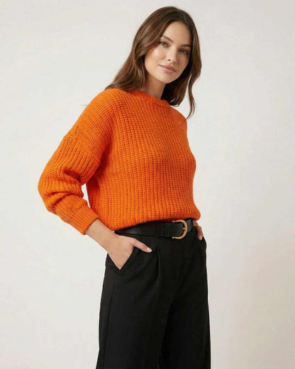 Model wearing the Sienna Sweater in bright orange, showcasing its relaxed silhouette and knit texture.