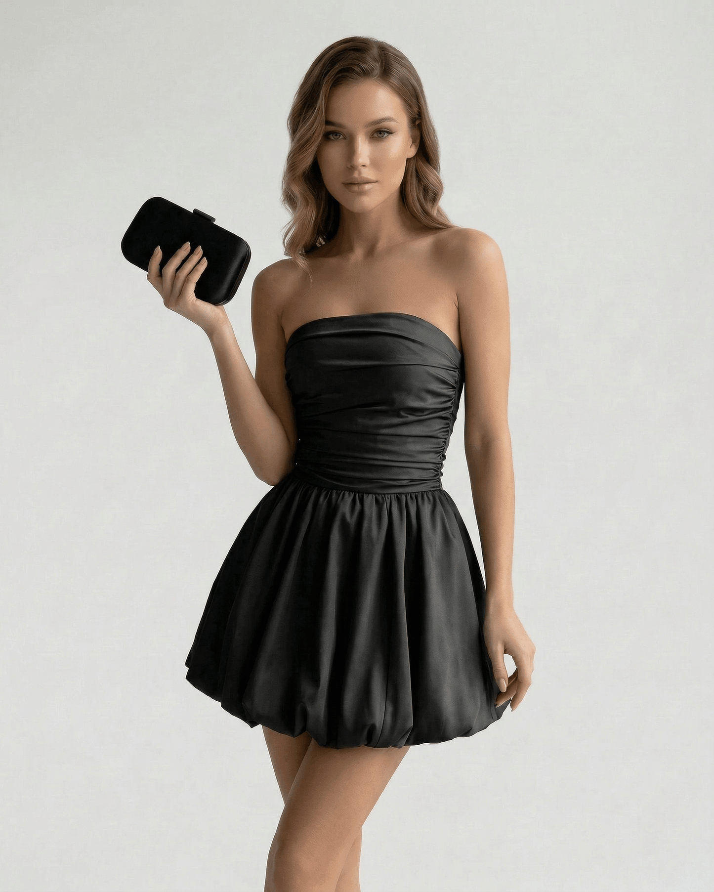 Model wearing the Voa Mini Dress in black satin, strapless design perfect for events and nights out, by RAMBLION.